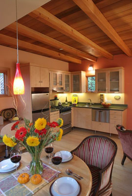 Breakfast nook and kitchen.   Glass panel upper cabinets, compact stainless steel appliances.