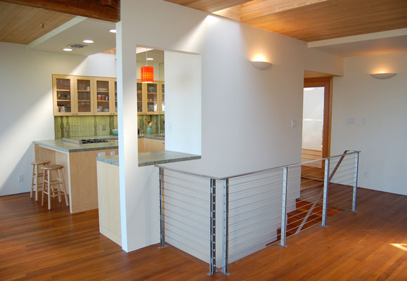 View from living room into kitchen, showing the open floor plan, new steel cable stair railing and entry.